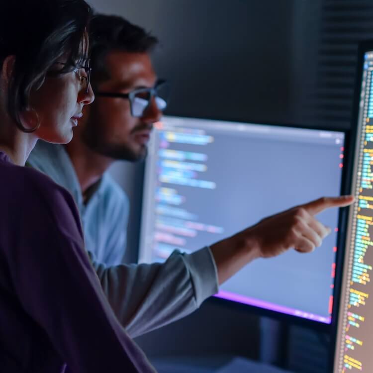 Two colleagues working together over multiple screens