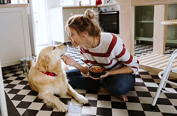 Happy woman playing with her dog in the kitchen