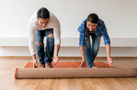 Couple rolling out a rug in their new home