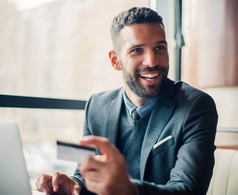man smiling while holding credit card