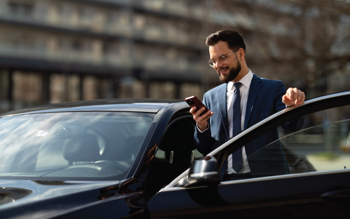 man looking at phone while entering car