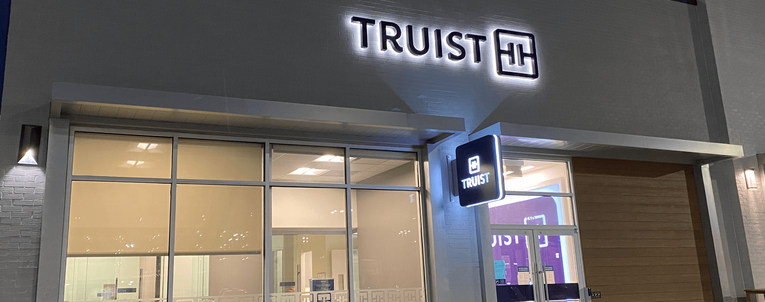 Image of a Truist bank branch lit up with LED lights at dusk. 