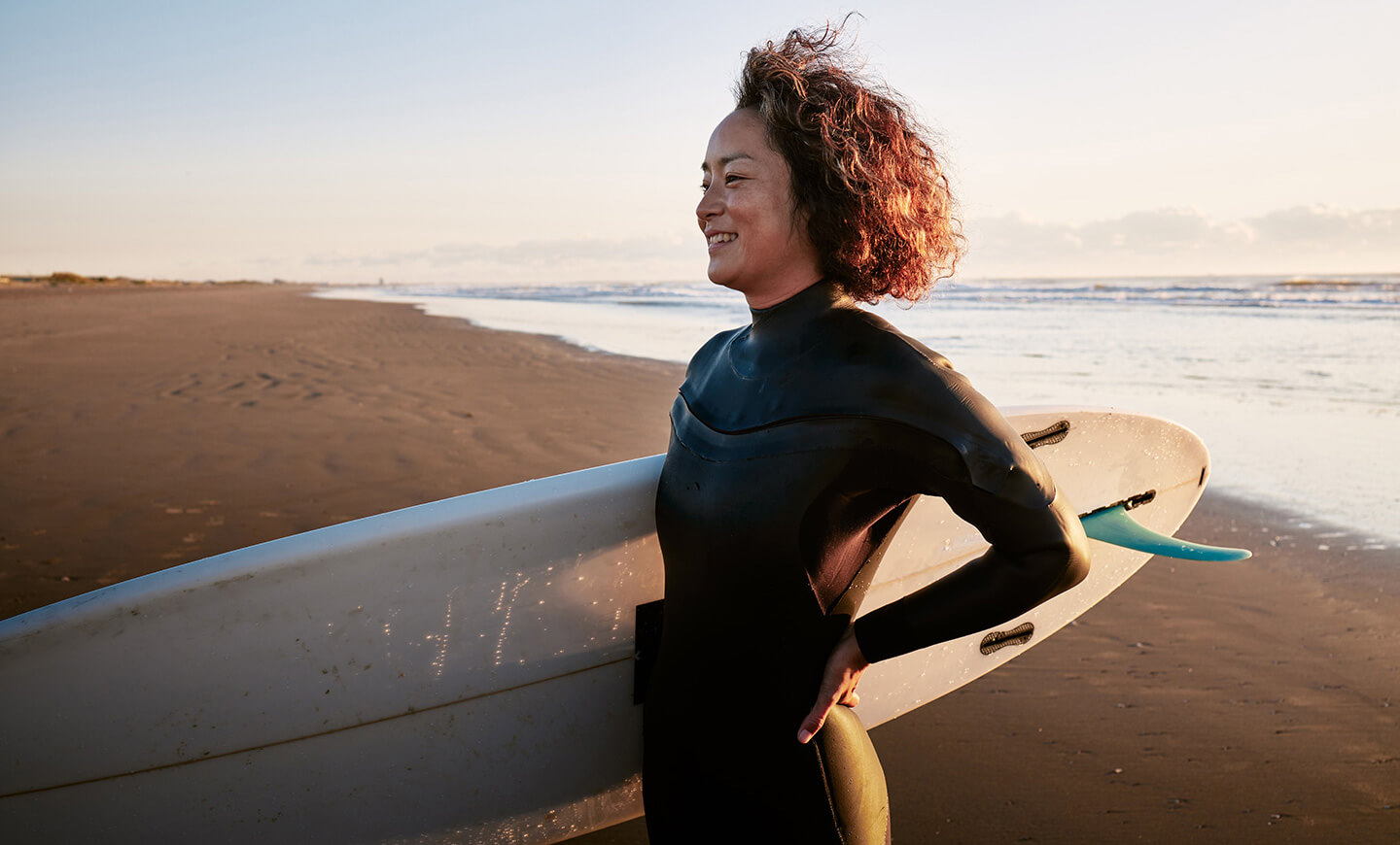 Mujer sosteniendo una tabla de surf en la playa